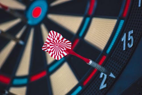 Goal dart board with dart that has missed its target and landed outside of the bulls eye