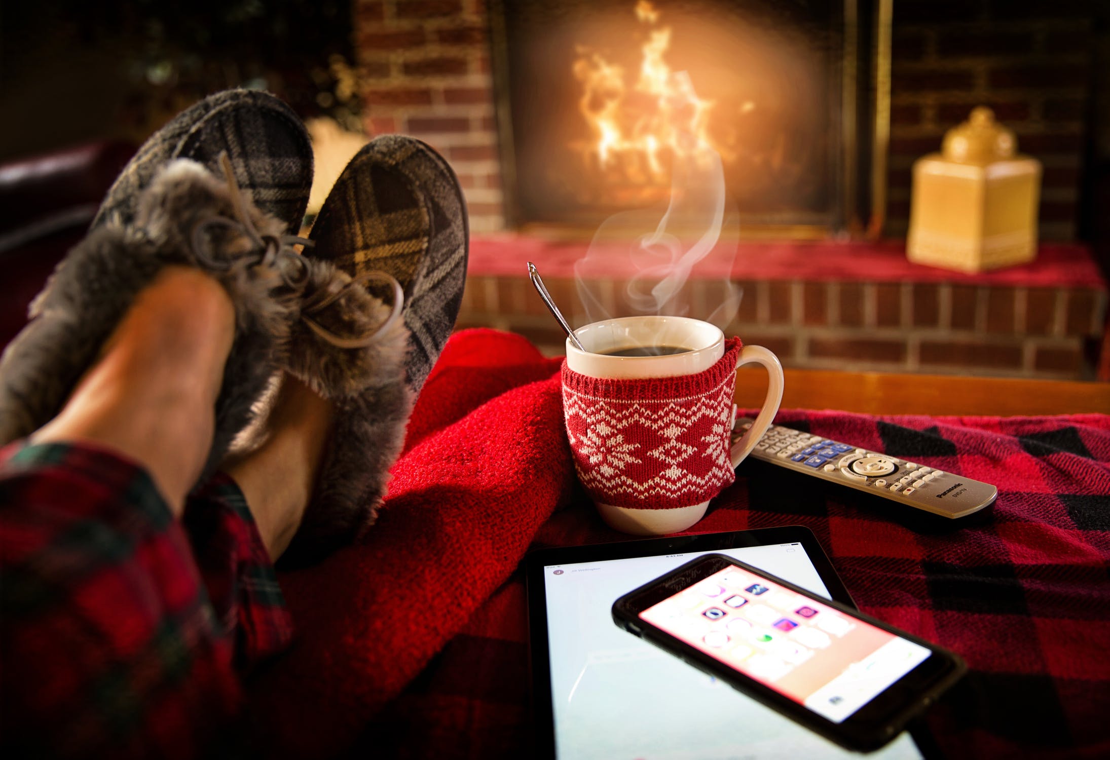 Woman wearing slippers and flannel pajamas sitting in front of cozy fire with steaming cup of hot chocolate free from financial worries by using the avalance method