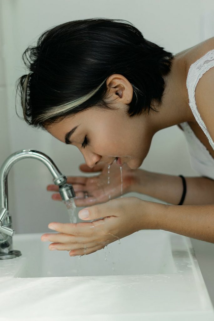 Woman with short dark hair washing her face
