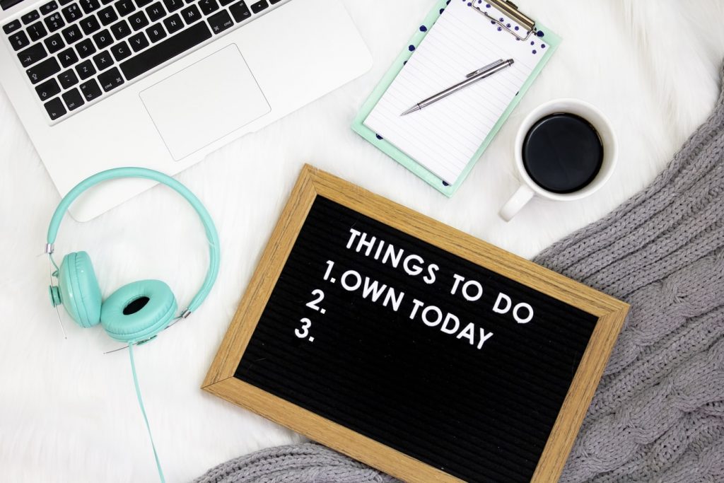 Notebook, computer, coffee, headphones and letterboard that reads "Things to do today"
