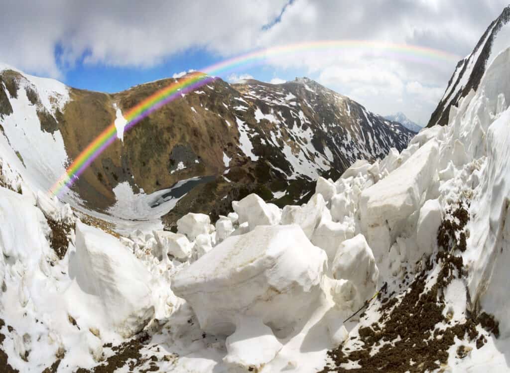 Debt Avalanche picture of avalanche of snow coming down mountain in Carpathians throwing out a rainbow