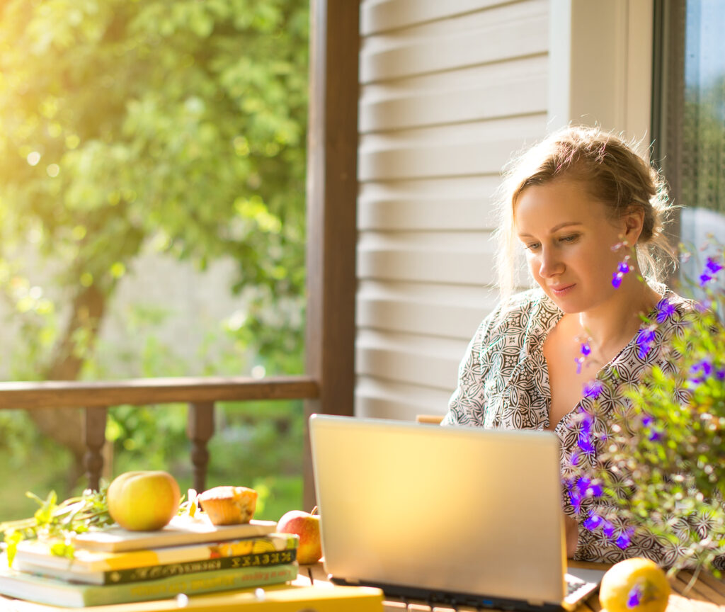 How to Become a Freelance Writer woman sitting at computer on a sunny porch