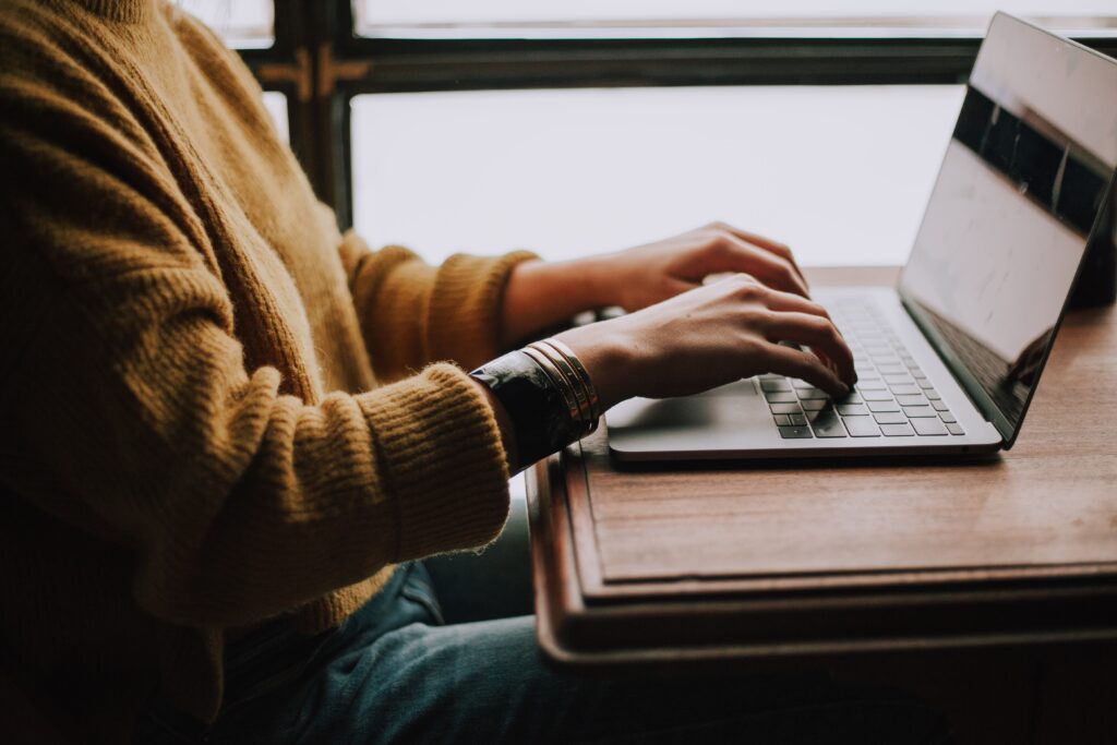 How to Become a Freelance Writer person in yellow sweater typing on computer