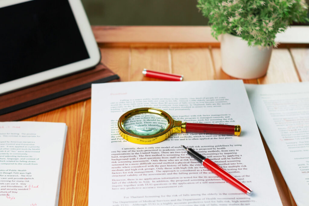 Online Proofreading Jobs papers on desk with magnifying glass and red pen