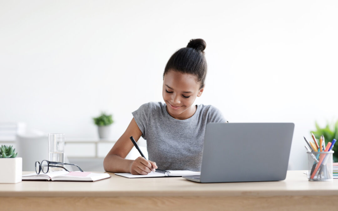 Stay at Home Jobs woman in gray shirt taking notes at computer desk